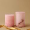 Two pink alabaster canisters of different sizes side by side on beige backdrop with gold ribbon