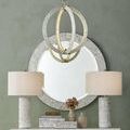 Chandelier in a room hung above a decorated console with oval mirror and matching lamps