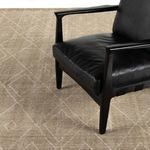 Taupe rug styled under a black leather armchair revealing scale and room context