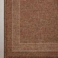 Close-up of woven rug surface and border pattern on smooth gray floor background