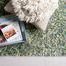 Rug placed on light wood floor with a tray and a cream textured pillow on top