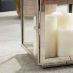 Close-up of polished chrome lantern door hinge and latch with white candle inside