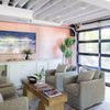 Rug under wood coffee table with two gray armchairs in a bright room with orange accent wall