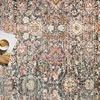Flat lay of rug surface with open book and candle, showing detailed pattern and color blending