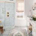 Teagan rug styled in bright bathroom with patterned tile floor, white cabinetry, and brass fixtures