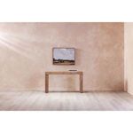 Dining table placed in minimalist room setting with textured beige walls and floor.