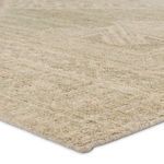Close-up angled view showing looped wool texture and subtle medallion pattern in green and cream tones
