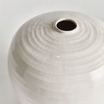 Close-up of glossy white reactive glaze highlighting concentric ring texture near narrow opening
