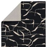 Folded corner edge of rug exposing smooth woven fabric backing in light grey tone.