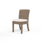 Armless outdoor dining chair with weathered tobacco all-weather wicker and white cushioned seat