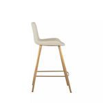 Profile view showing stool's slim gold legs and gently curved seat edge