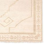 Close-up of corner showing detailed medallion and intricate border with cream fringe