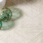 Close-up on ivory rug texture under glass floats with jute netting on natural fiber weave
