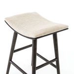 Angled top view of stool highlighting saddle-shaped upholstered seat and dark wood frame