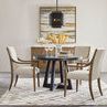Small dining setup with four Chapman Upholstered Arm Chairs around round black pedestal table on geometric rug