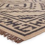 Close-up of flatwoven jute texture with black geometric patterns and knotted fringe detail