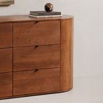 Close-up angled side view of oak dresser showing rounded edge and lower drawers