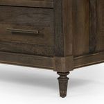 Detailed close-up of turned wooden leg with weathered chestnut finish at bottom corner of dresser