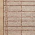Top-down view focusing on the woven texture and blush linear grid near rug’s edge on light wood floor