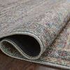 Corner of rug partially rolled to reveal dark black backing and thin pile thickness