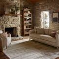 Townes Rug styled in rustic living room with stone walls, beige sofa, and wood floors