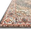 Close-up angled view showing the rug's textured pile and detailed border in blue, cream, and rust colors