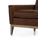 Close-up of vertical leather stitching on backrest with natural creases and patina.