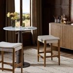 Two Aya Counter Stools styled in cozy bar setting with wood cabinetry, marble table, and rug