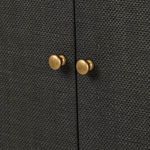 Close-up of antique brass round knobs on black woven raffia cabinet doors