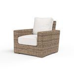 Front-angle view of Havana Club Chair showcasing woven Aged Tobacco wicker and plush beige cushions