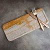 Travertine tray on textured surface styled with bronze knife and fork on top