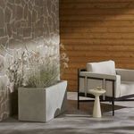 Outdoor patio setting showing planter with ornamental grasses beside modern chair and table