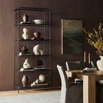 gunmetal bookcase styled in a room with pottery, books, and dining table against dark brown wall