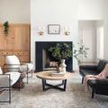 Jules rug placed in bright modern living room with white walls, black sofa, and natural wood table