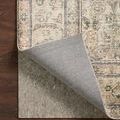 Patterned rug corner folded back to show rug pad beneath and its textured gray upper surface
