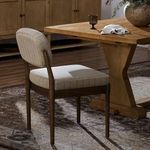 Esther Dining Chair placed next to wooden dining table on patterned rug in warm, styled room