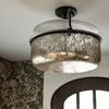 Ceiling-mounted lantern with clear glass disk above metal frame and patterned wallpaper background