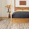 Bedroom context showing Reyla Granite Mocha Rug fully laid out with wood bed frame and wall art