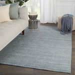 Rug styled in a living room next to beige sofa and side table on dark wood floor