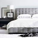 Lasalle king bed styled in a bright modern bedroom with white bedding, black bedside table, lamp, and decorative framed art