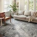 Austen Pebble / Charcoal Rug styled in bright living room with beige sofa and wooden chair