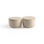 Salt jar among stacked ceramic bowls and plates on wooden table with subdued lighting