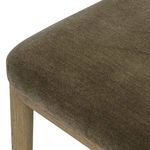 Close-up of rounded front edge of velvet seat cushion with amber wood chair leg partially visible