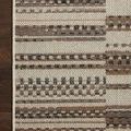 Top-down close-up of Rainier Ivory Taupe rug corner highlighting woven patterned design on dark hardwood floor.