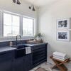 Small rug styled in bright kitchen with navy blue cabinets and white walls under window
