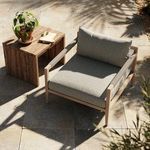 Outdoor setting with the chair on tile flooring next to a wooden side table and plant