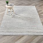 Del Mar rug styled in room with wood herringbone floor and light stool on corner of rug