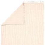 Back corner of cream geometric rug flipped to show woven underside and fringe