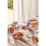 Tarifa high ball glass with blue rim in outdoor table setting, hand pouring liquid into another glass