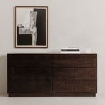 Dresser styled in minimalist room under abstract art with books and small sculpture on top